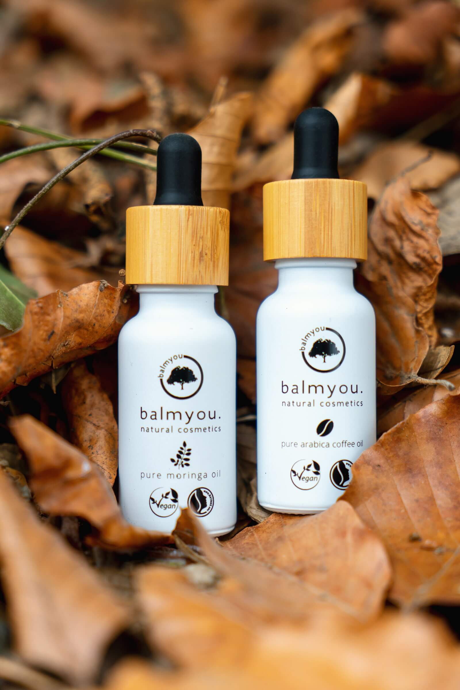 XUSCHA Design – Editorial Design – Balmyou Naturkosmetik – Produktfotografie in der Natur. Zwei Öle umgeben von Herbstblättern.